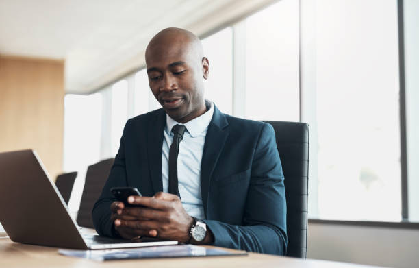 Corporate, black man and manager with smartphone, typing and laptop with connection, social media and online reading. African American male employee, consultant and ceo with technology and success